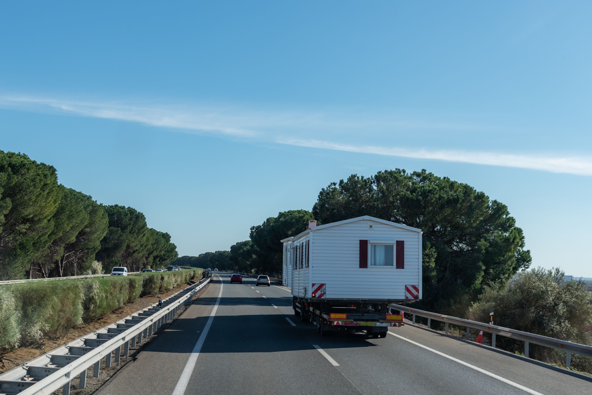Bulky road transport of mobile prefabricated homes, oversized vehicle. Rear view.