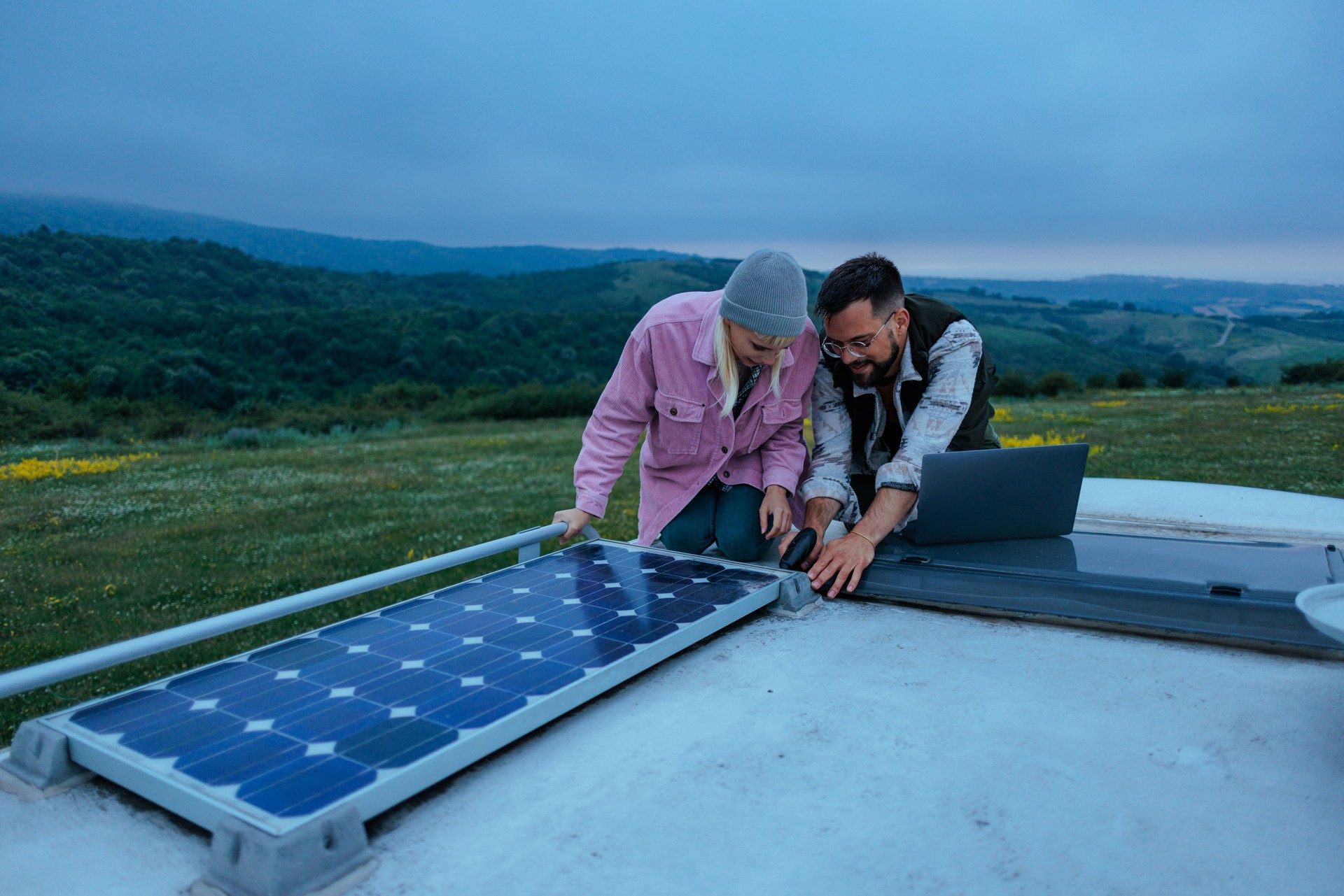 Technicians installing solar panel on recreational vehicle roof in the evening